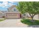Charming two-story home featuring a red brick facade, manicured lawn, and mature shade tree at 10115 Cook St, Thornton, CO 80229