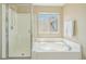 Relaxing main bathroom featuring a soaking tub, glass-enclosed shower, and a window for natural light at 10115 Cook St, Thornton, CO 80229