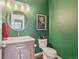 Stylish powder room with green accent wall, modern vanity, framed art, and decorative mirror at 10115 Cook St, Thornton, CO 80229