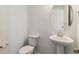 Modern powder room with a pedestal sink, toilet, and round mirror at 455 S Salida St, Aurora, CO 80017