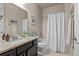 Stylish bathroom features a shower/tub with white curtain, framed mirror and neutral tile flooring at 15230 W Baker Ave, Lakewood, CO 80228