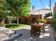 Lush backyard featuring a stone patio with dining set and mature trees providing shade and privacy at 562 N Pennsylvania St, Denver, CO 80203