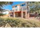 Backyard view of a beautiful home with a large deck, covered patio, and mature trees at 9554 E Hidden Hill Ln, Lone Tree, CO 80124