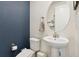 Charming powder room featuring pedestal sink, toilet, and painted blue accent wall at 19316 W 84Th Pl, Arvada, CO 80007