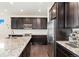 Bright kitchen with stainless steel appliances, granite counters, and dark wood cabinetry at 19316 W 84Th Pl, Arvada, CO 80007