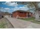 Charming brick home featuring a long driveway leading to a detached two-car garage and landscaped front yard at 7747 Quivas St, Denver, CO 80221