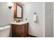 Charming half bathroom with wood vanity, decorative mirror, and ample lighting at 444 Vance St, Lakewood, CO 80226