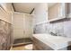 Tiled bathroom featuring a shower with glass doors, a toilet, and a gray wooden cabinet with a marble countertop at 6374 Upham St, Arvada, CO 80003