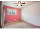 Cozy bedroom with pink accent wall, carpet flooring, and a window providing natural light at 6374 Upham St, Arvada, CO 80003