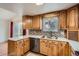 Traditional-style kitchen featuring wooden cabinets, tile backsplash, stainless steel dishwasher, and bright natural lighting at 6374 Upham St, Arvada, CO 80003