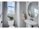 Small bathroom with pedestal sink, toilet, and circular mirror at 23320 E Berry Ave, Aurora, CO 80016