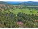 Breathtaking aerial view of a home in a lush, green landscape with rolling hills in the background at 7585 Native Dancer Trl, Evergreen, CO 80439