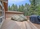 Large wooden back deck with a large rock, grill, wooden railings, and tall trees at 7585 Native Dancer Trl, Evergreen, CO 80439