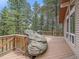 Back deck with trees, rock, grill, and wooden railings at 7585 Native Dancer Trl, Evergreen, CO 80439