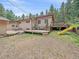 Backyard view showcasing a spacious deck, lush greenery, and mature trees at 7585 Native Dancer Trl, Evergreen, CO 80439