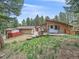 Exterior backyard view with wooden decks and a swing, surrounded by lush greenery at 7585 Native Dancer Trl, Evergreen, CO 80439