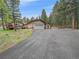 Exterior view of the home, garage, and long driveway with lush trees surrounding at 7585 Native Dancer Trl, Evergreen, CO 80439