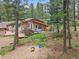 Exterior of a home with wooden decks and play area among the trees at 7585 Native Dancer Trl, Evergreen, CO 80439