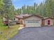 Charming home featuring a two-car garage and wooden deck surrounded by mature trees at 7585 Native Dancer Trl, Evergreen, CO 80439
