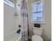 Bright bathroom featuring a tiled shower with a shower curtain and a window at 10992 Xanadu St, Commerce City, CO 80022