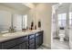 Bathroom features a double sink vanity with dark cabinets, a large mirror, and tiled floors at 10992 Xanadu St, Commerce City, CO 80022