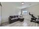 This bonus room includes wood-look floors and a comfortable gray couch near a bright window at 10992 Xanadu St, Commerce City, CO 80022