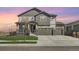 Beautiful two-story home with a three-car garage, stone accents, and a well-maintained lawn at 10992 Xanadu St, Commerce City, CO 80022