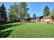 Spacious backyard with a large, well-maintained lawn, mature trees, and patio area at 3666 S Jersey St, Denver, CO 80237