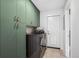 Well-organized laundry room featuring modern washer/dryer, stylish sage green cabinets, and tiled flooring at 3666 S Jersey St, Denver, CO 80237