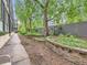 Building backyard, showcasing mature trees, tidy garden beds, and a shaded patio area at 1050 N Corona St # 105, Denver, CO 80218