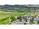 This is an aerial view of houses in a neighborhood with paths and a large grassy field and mountain views in the distance at 9721 Marmot Ridge Cir, Littleton, CO 80125