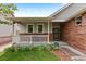 Inviting covered front porch featuring a white railing, brick accents, and manicured landscaping at 1901 S Union Pl, Lakewood, CO 80228