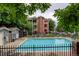 Community pool with lounge chairs surrounded by trees and a fenced in area at 2430 W 82Nd Pl # 2F, Westminster, CO 80031