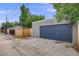 A detached garage with a new blue garage door is visible and is next to a driveway and a wood fence at 3881 Zenobia St, Denver, CO 80212