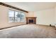 Bright living room featuring a brick fireplace, a large window, and neutral carpeting at 2561 Cactus Bluff Pl, Highlands Ranch, CO 80129