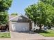 A well kept one-story home with gray siding, stone accents, a two car garage and a beautiful front yard at 8915 W Quarto Pl, Littleton, CO 80128