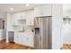 Updated kitchen with stainless steel refrigerator, white cabinets, countertops, and hardwood floors at 2085 S Deframe St, Lakewood, CO 80228