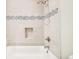 Bathtub features light gray tile, a mosaic tile accent strip, and a built-in niche at 3970 Longwood Ave, Boulder, CO 80305
