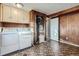 Functional laundry room with washer, dryer, cabinets, utility sink, and wood-paneled accent wall at 2925 S Ingalls Way, Denver, CO 80227