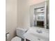 This bathroom features a toilet, sink, and mirror with an open view of the kitchen at 395 Raspberry Ln, Monument, CO 80132