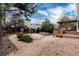 Gravel backyard with an outdoor kitchen including a deck with a pergola, surrounded by lush greenery and a fence at 8129 Locust Dr, Littleton, CO 80125
