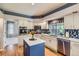 Kitchen featuring a blue island, white cabinetry, stainless appliances, and quartz countertops at 5305 W Lake Pl, Littleton, CO 80123