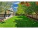 Lush backyard showcasing a manicured lawn, mature trees, and a charming patio area, ideal for relaxation at 6488 Tilbury Ave, Firestone, CO 80504