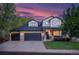 Charming two-story home with a manicured lawn, stone accents, and a spacious three-car garage at dusk at 6488 Tilbury Ave, Firestone, CO 80504