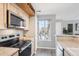 Well-lit kitchen featuring stainless steel microwave, granite countertops, and wooden cabinets at 13782 E Lehigh Ave # B, Aurora, CO 80014