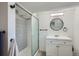 Bright bathroom featuring tiled shower with glass door, modern vanity, and round mirror at 4556 Decatur St, Denver, CO 80211