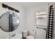 Bright bathroom with a round mirror, unique lighting fixtures, and black and white checkered shower curtain at 4556 Decatur St, Denver, CO 80211