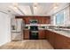 Cozy kitchen featuring stainless steel appliances, wood cabinets, granite countertops, and hardwood floors at 9042 E Lehigh Ave, Denver, CO 80237