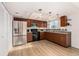 Modern kitchen with stainless steel appliances, wood cabinets, granite countertops, and hardwood floors at 9042 E Lehigh Ave, Denver, CO 80237