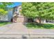 Two-story home featuring an attached two-car garage and a mature tree in the front yard at 293 Wagonwheel Dr, Fort Lupton, CO 80621